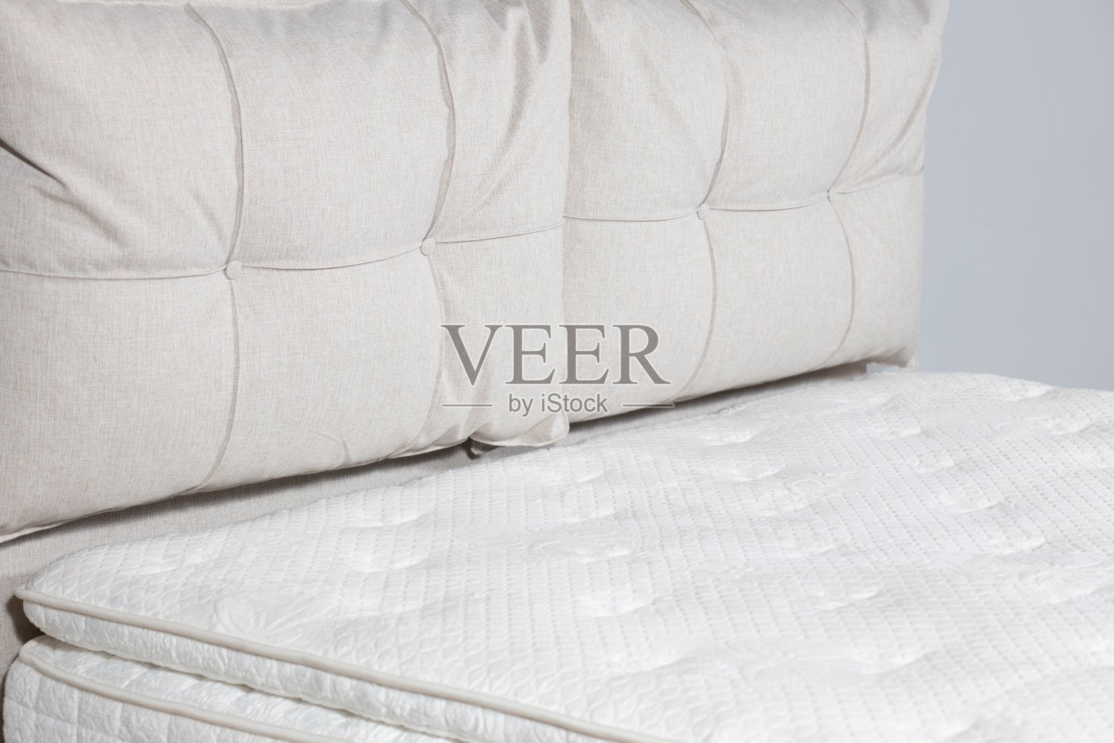 一张床的特写镜头,米色的织物内饰,白色的床垫,大枕头照片摄影图片