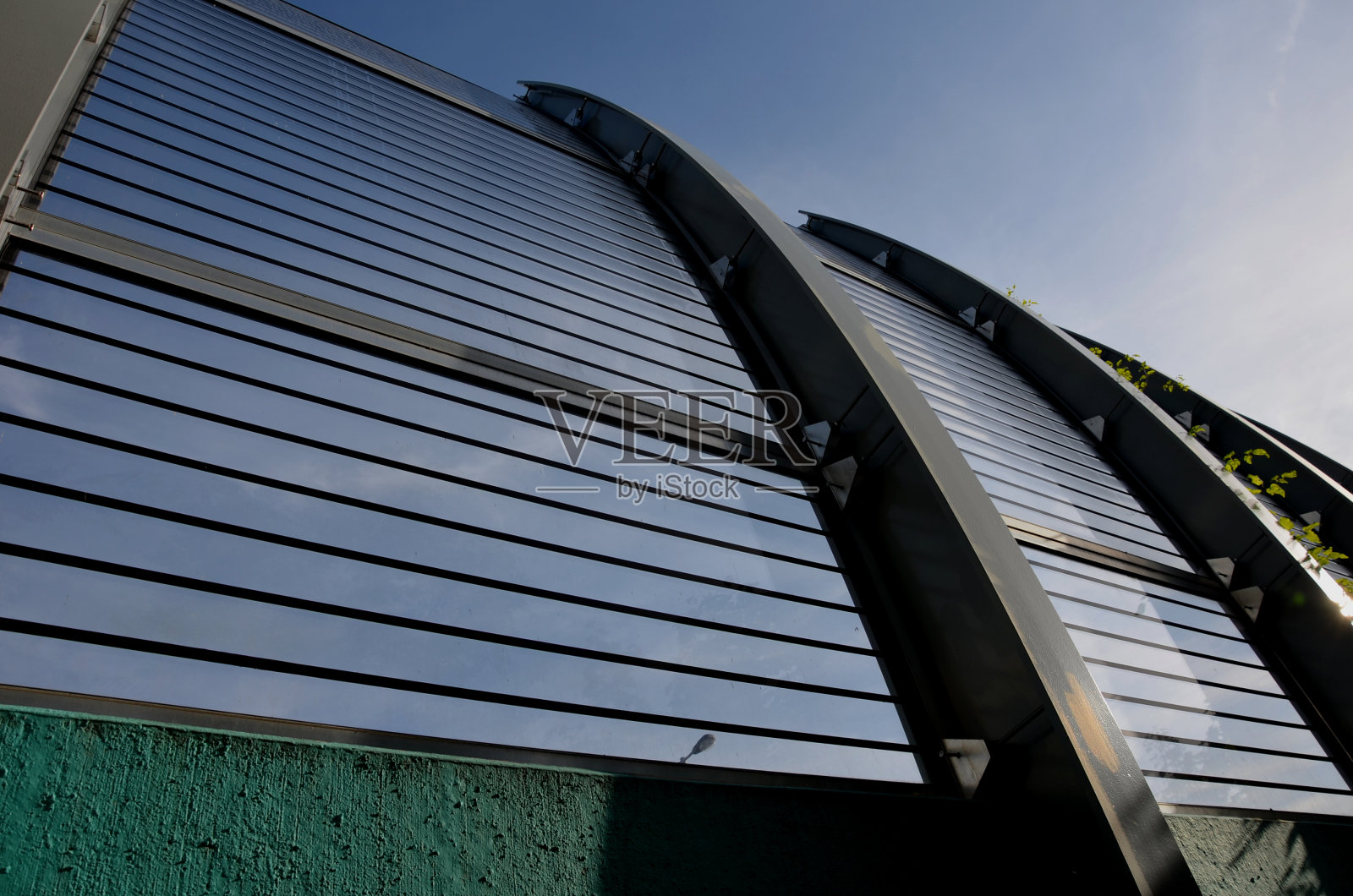 隔音墙的条纹玻璃在高速公路大桥上嵌入金属梁,在街道上。用压力螺丝固定窗户。多孔的石块在道路上方弯曲倾斜,对角线,向上攀升照片摄影图片