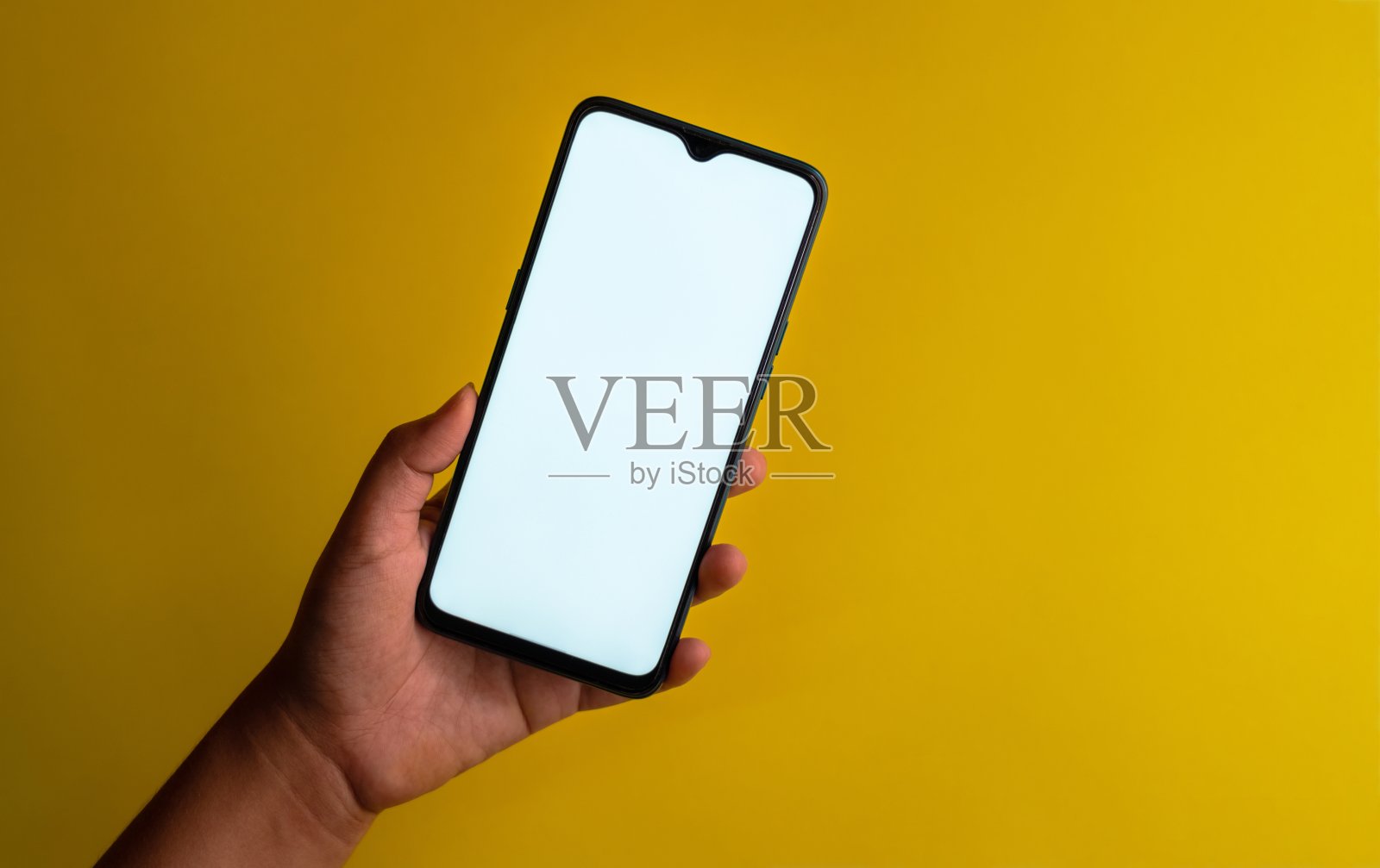 拿着黄色背景的智能手机的人照片摄影图片