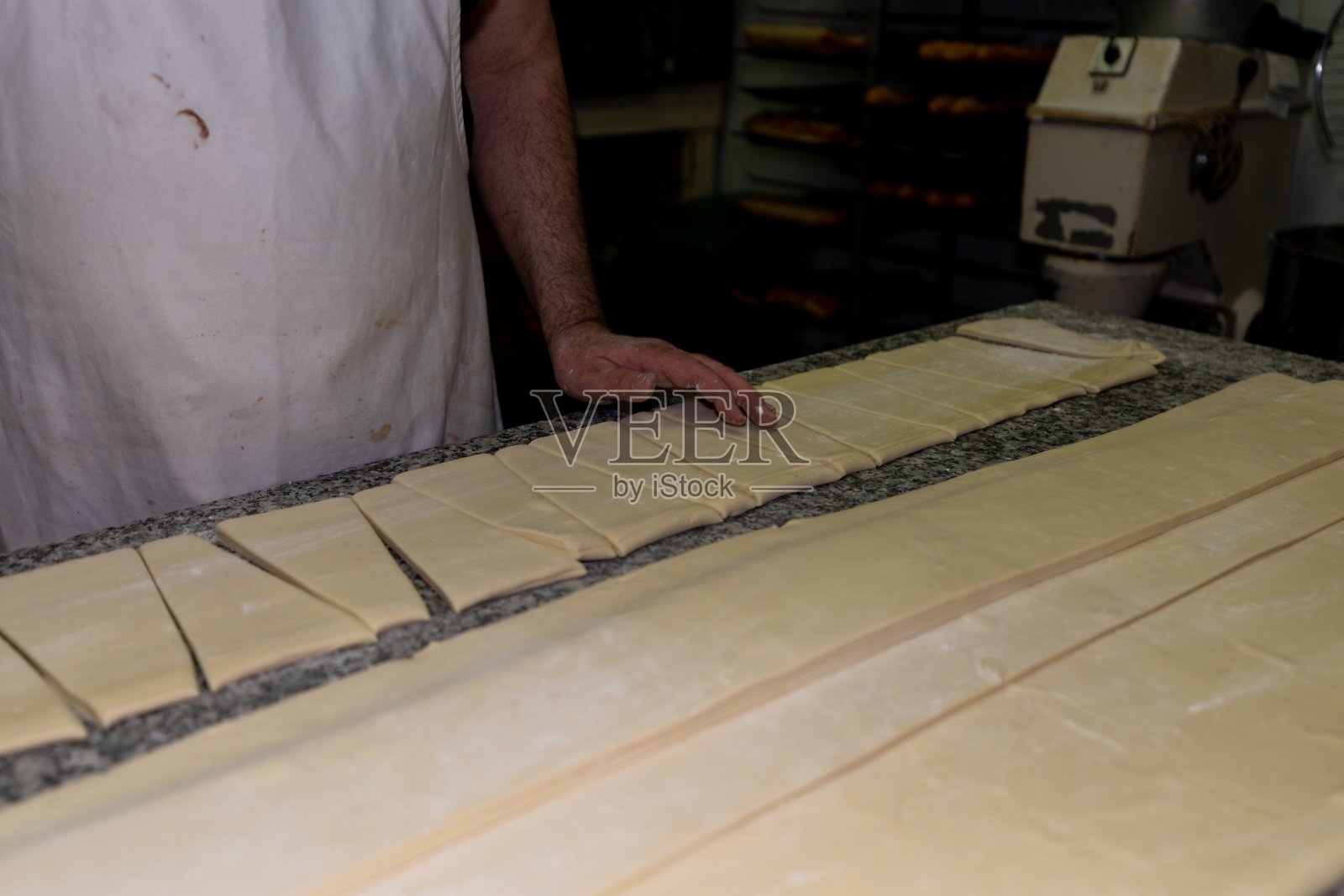 面包师把面团切成三角形,在糕点店做牛角面包照片摄影图片