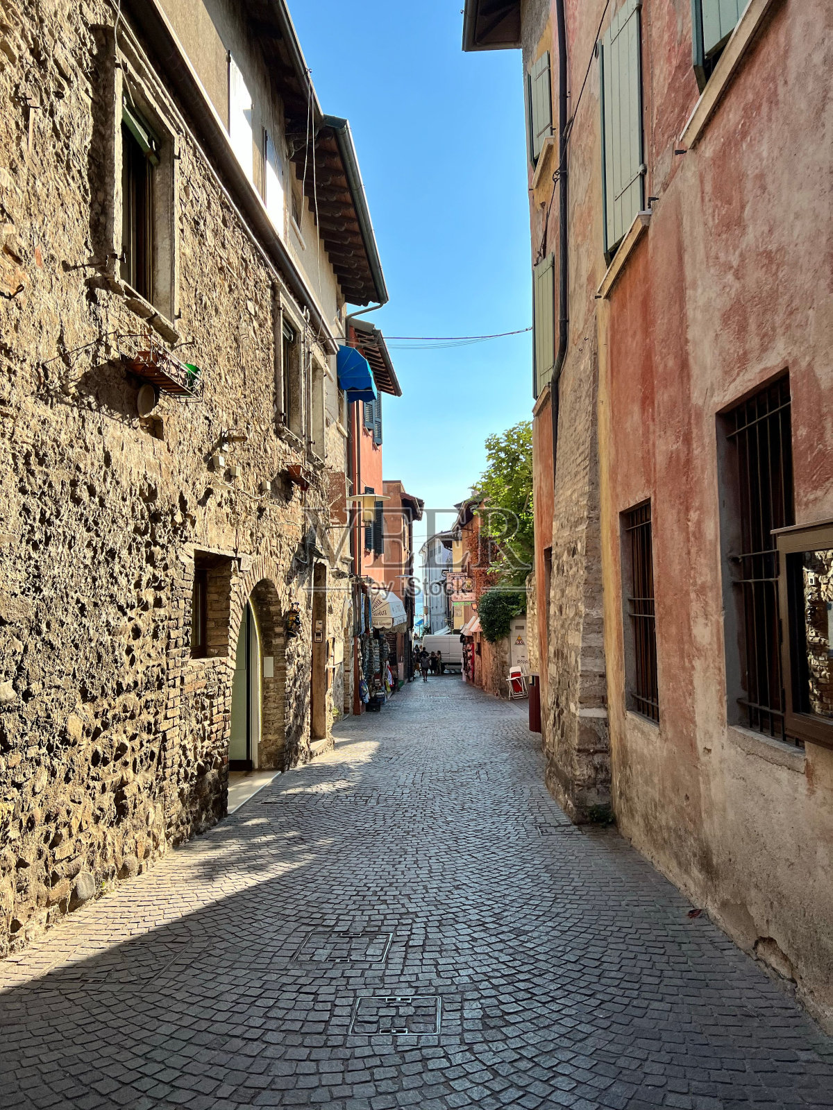 在蓝天下,一条狭窄的小巷在古老的石头房子之间垂直拍摄照片摄影图片