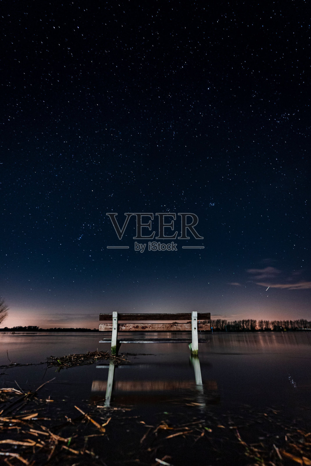 夜晚水中长凳的垂直镜头照片摄影图片