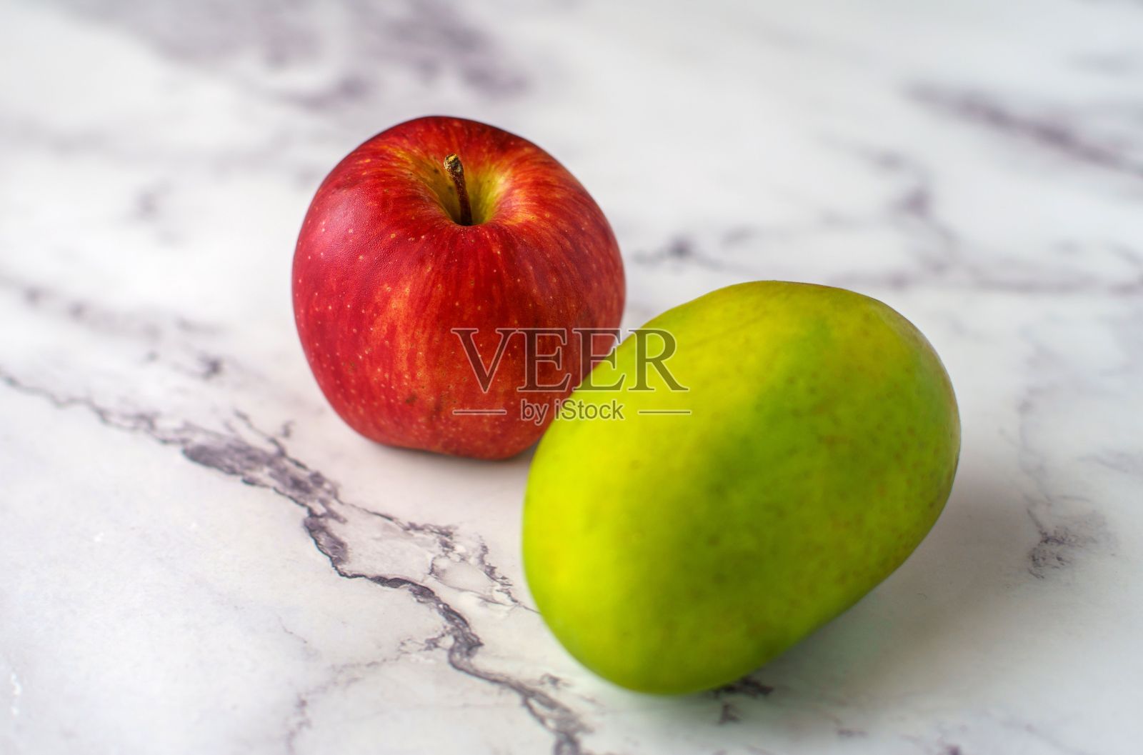 红苹果和绿芒果放在大理石柜台上照片摄影图片