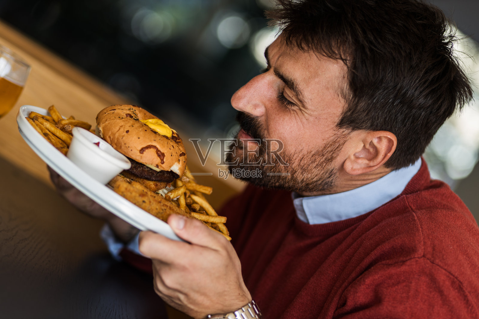 在辛苦工作了一天后,迷人的商人闻着汉堡的香味照片摄影图片