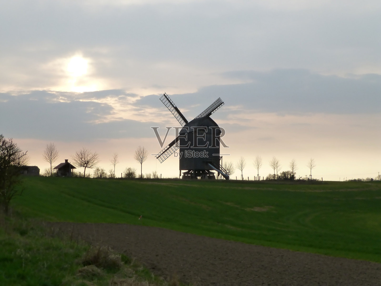 夕阳下的老风车。照片摄影图片