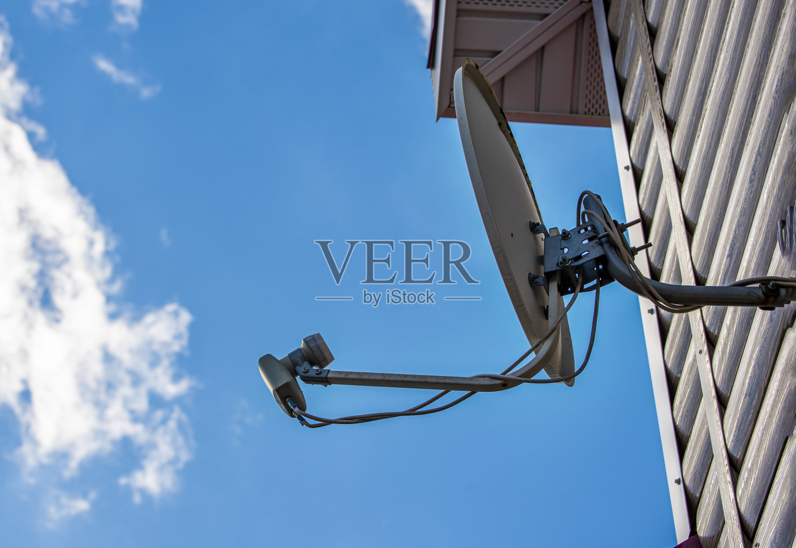 蓝色的天空映衬着房子墙上的电视卫星天线照片摄影图片