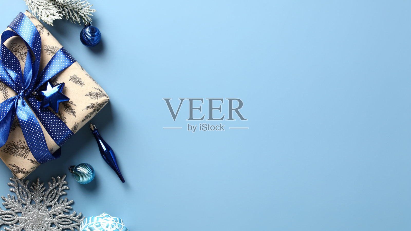 圣诞礼品盒与蓝色丝带蝴蝶结,雪杉树枝,饰品在柔和的蓝色背景。平铺,俯视图。照片摄影图片