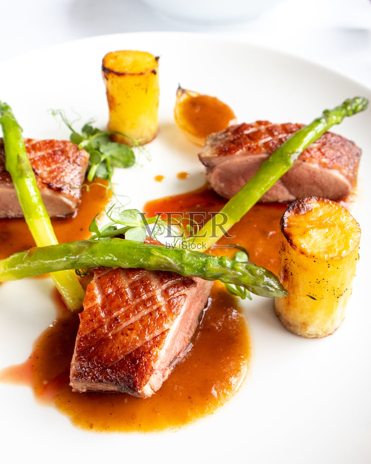 垂直的烤肉配上酱汁和芦笋放在盘子里照片摄影图片