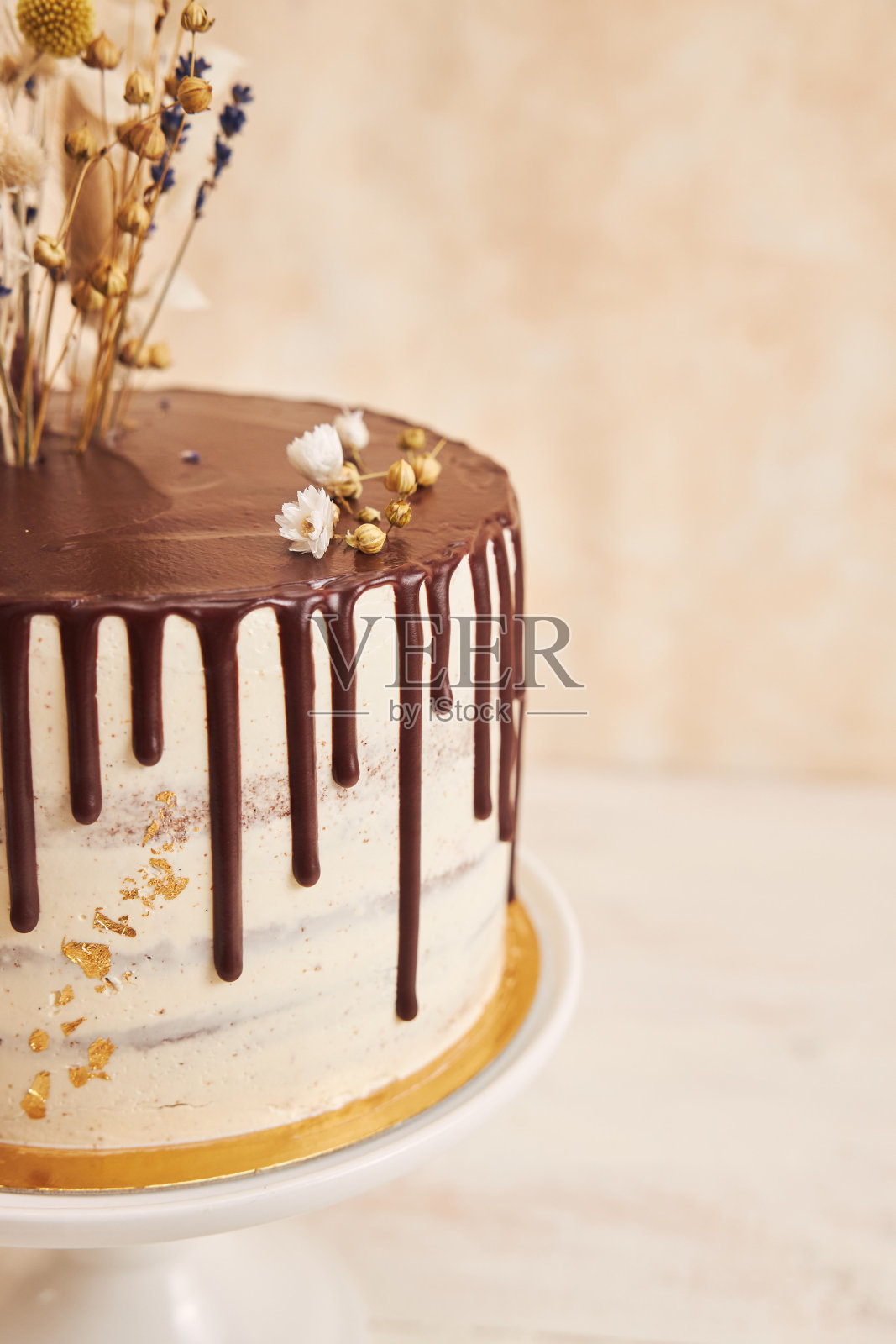 垂直拍摄的香草蛋糕与巧克力滴和花在上面照片摄影图片