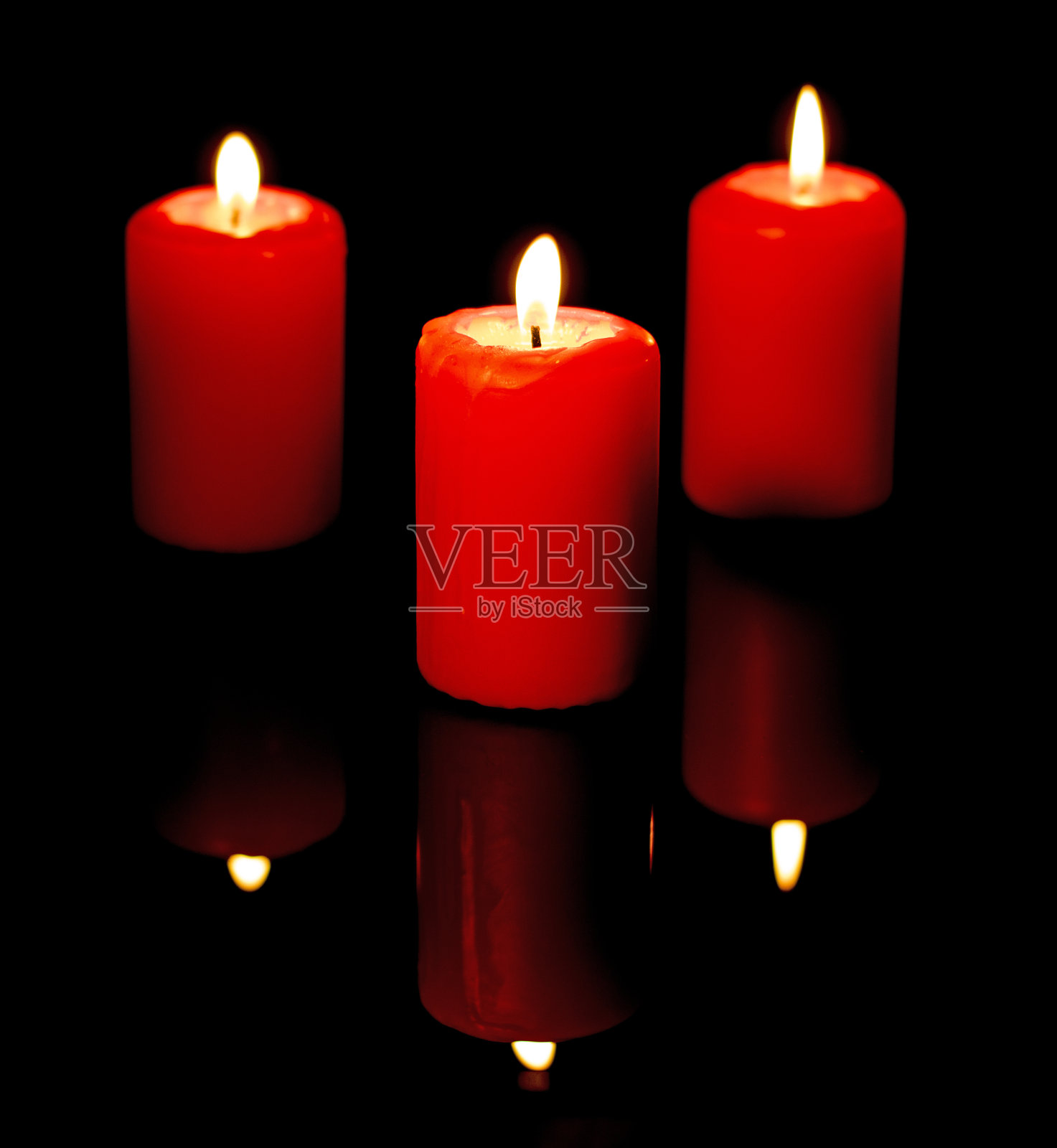 三支燃烧的红蜡烛映照在黑色的镜子背景中照片摄影图片