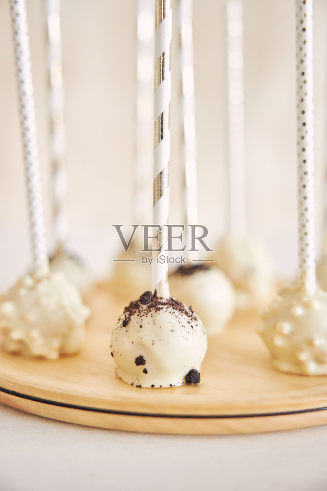 垂直特写拍摄美味的白色蛋糕棒棒糖在白色背景和木桌照片摄影图片