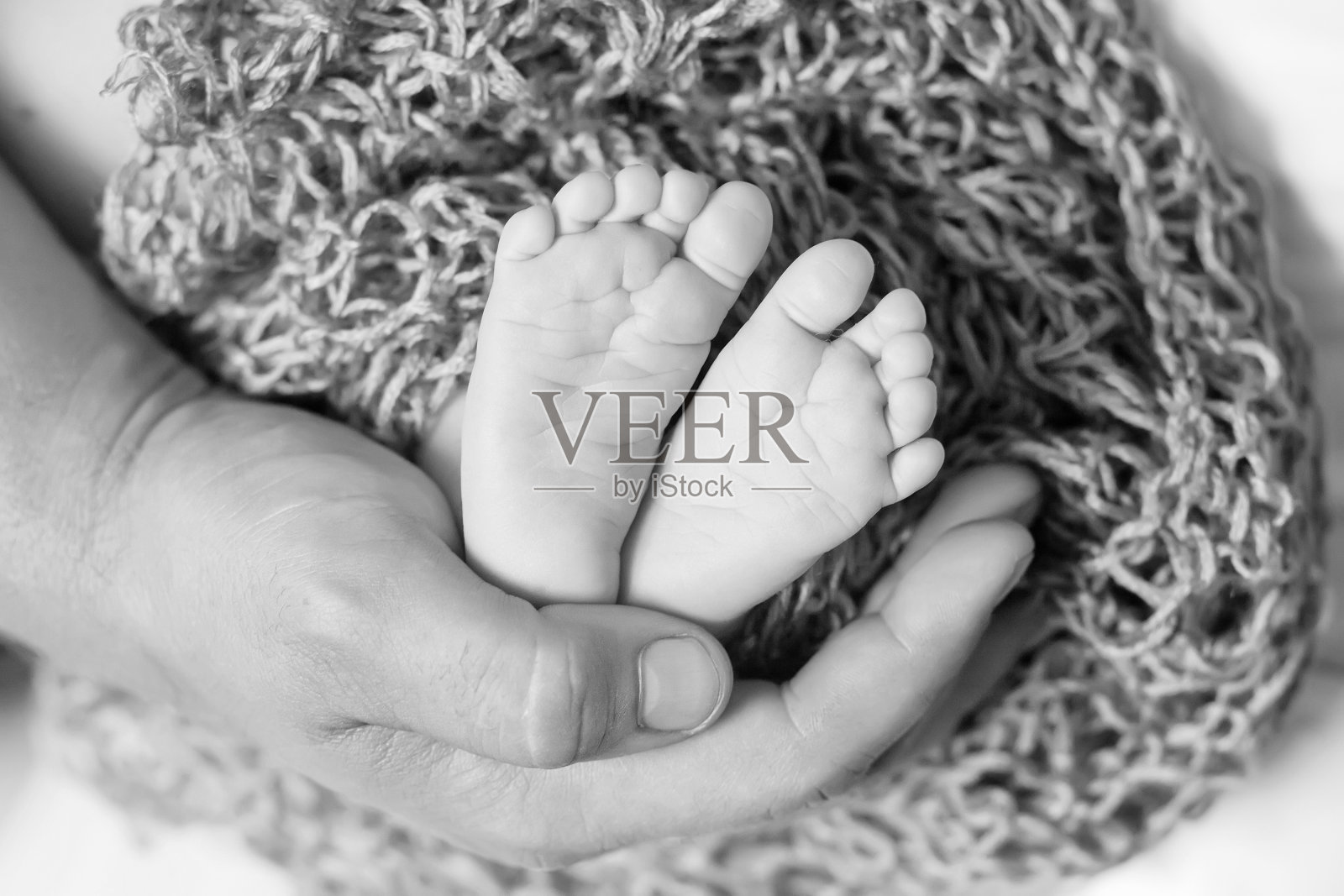 婴儿的脚在父亲的手里。小新生儿的脚在男性形状的手特写。爸爸和他的孩子。幸福的家庭的概念。照片摄影图片