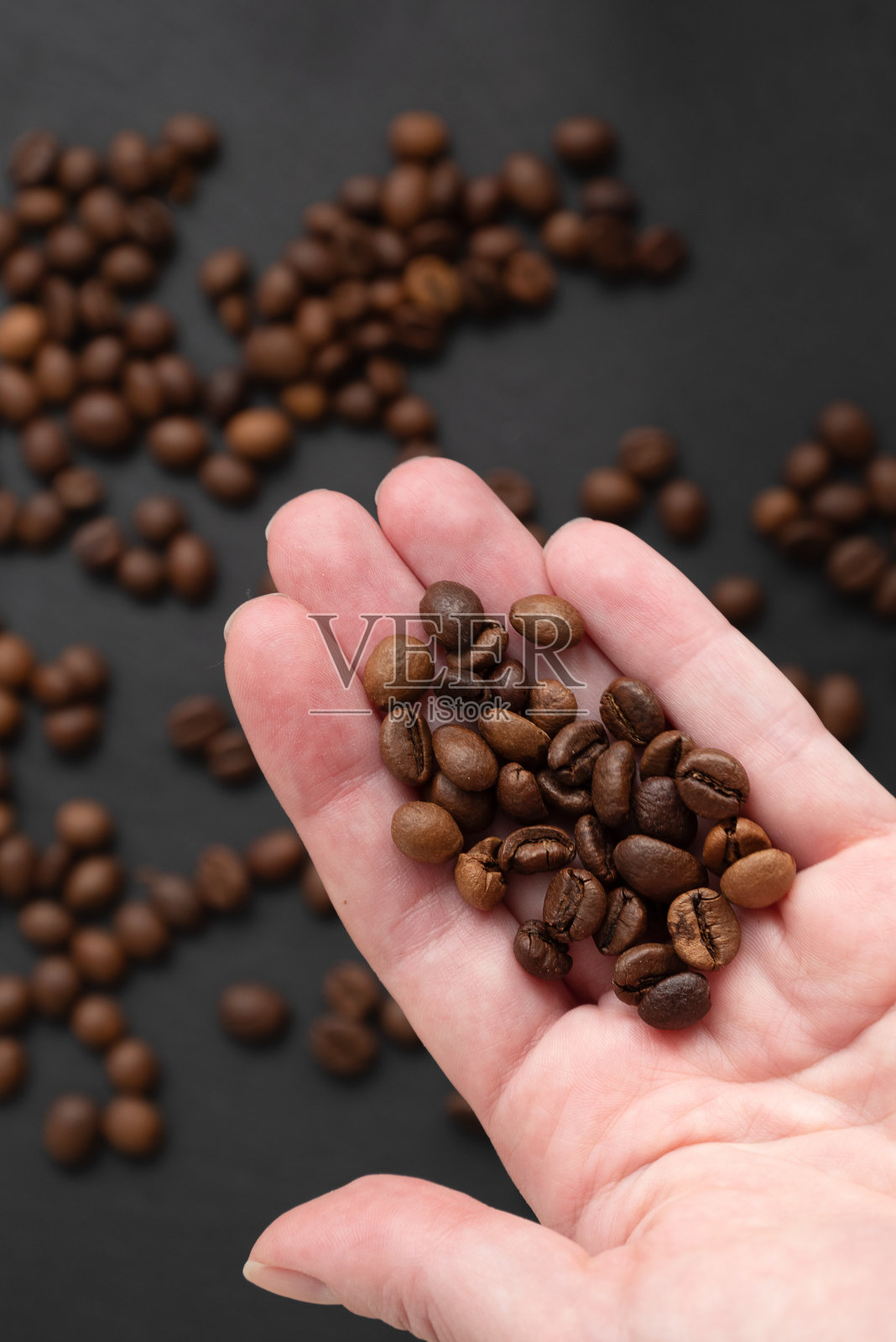 烤咖啡豆在人的手掌上,黑色的背景照片摄影图片
