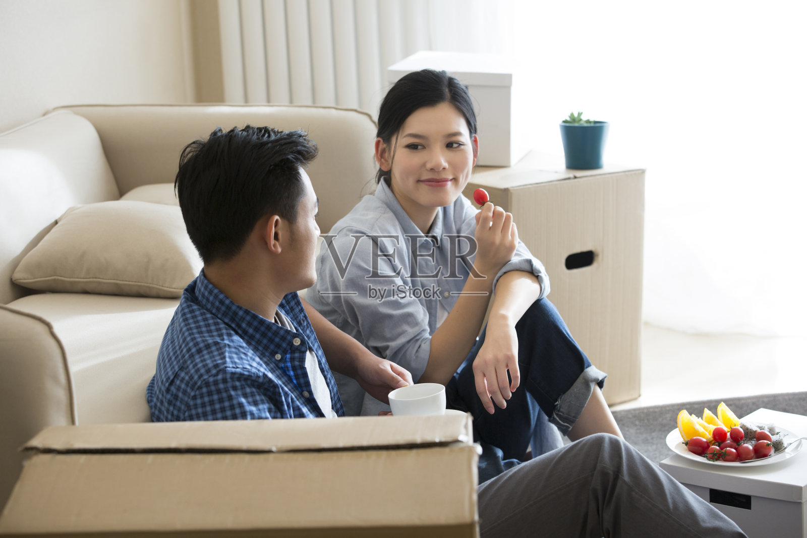 刚搬进新家的年轻夫妇,坐在地板上吃水果,喝咖啡休息——库存照片照片摄影图片