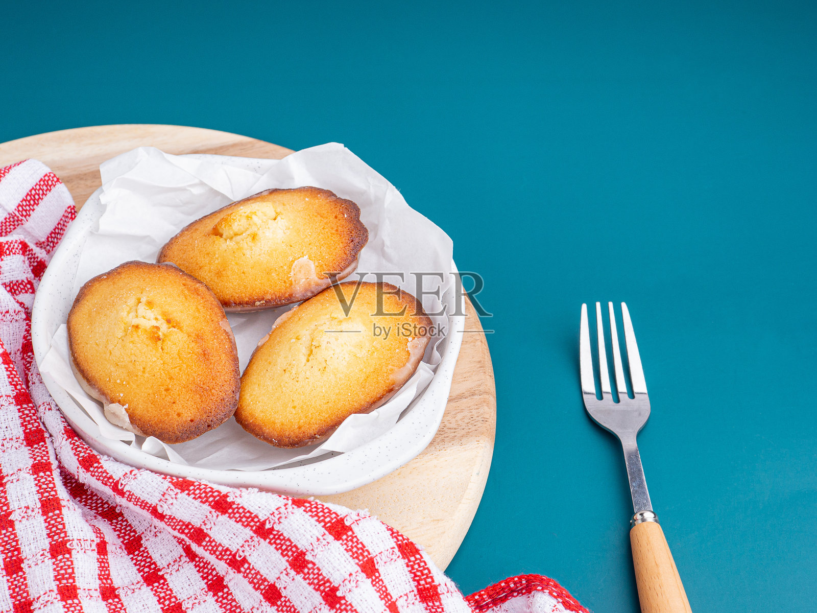 柠檬釉玛德琳蛋糕放在盘子里,背景是蓝色的灯光。照片摄影图片