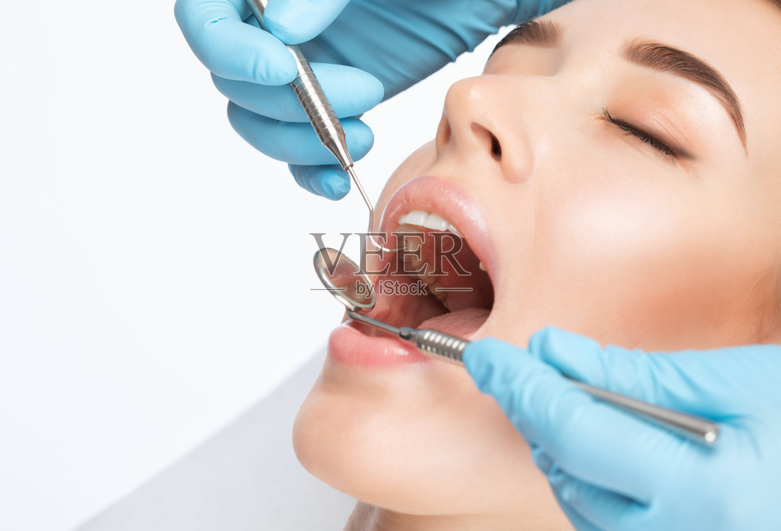 牙科医生在牙科诊所为一位年轻漂亮的女士治疗龋齿。牙齿充填。照片摄影图片