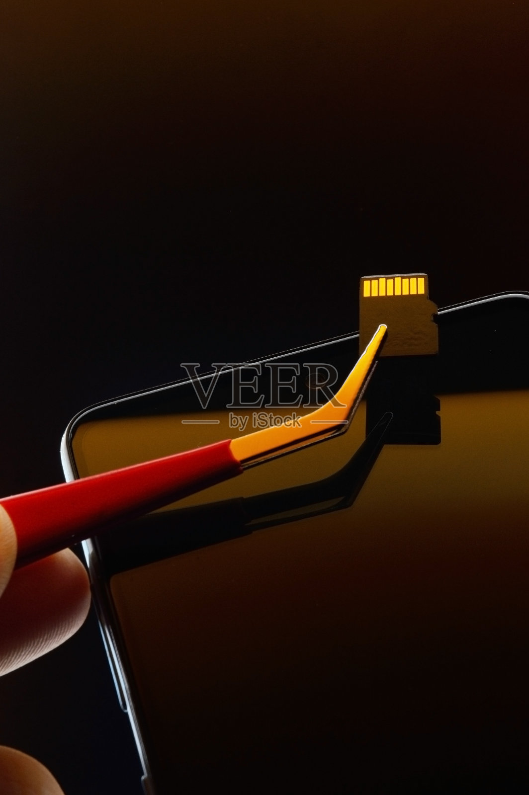 关掉智能手机,用镊子把micro sd卡拔出来照片摄影图片