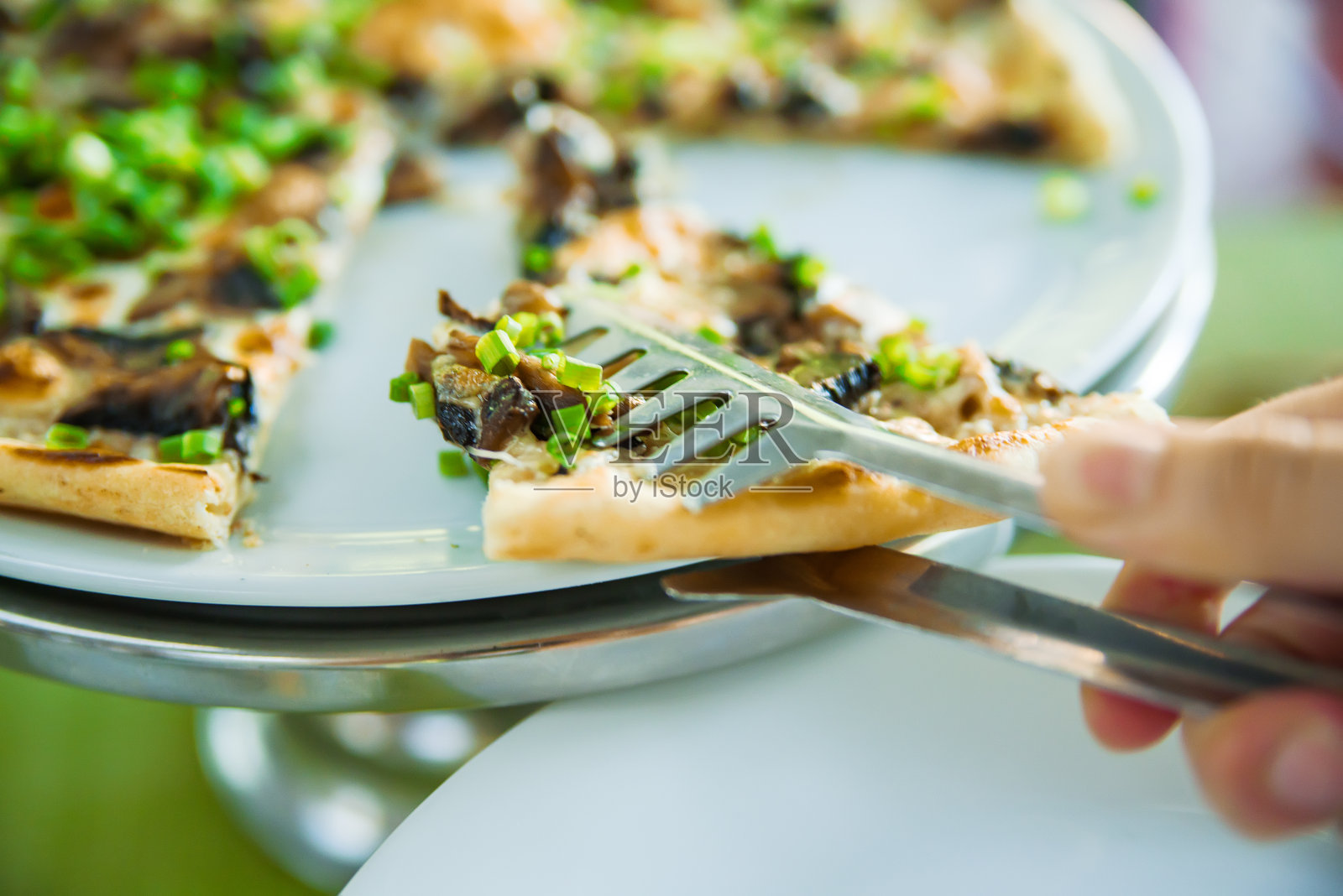 片披萨。餐馆里有披萨的桌子。披萨在绿色上的特写照片摄影图片