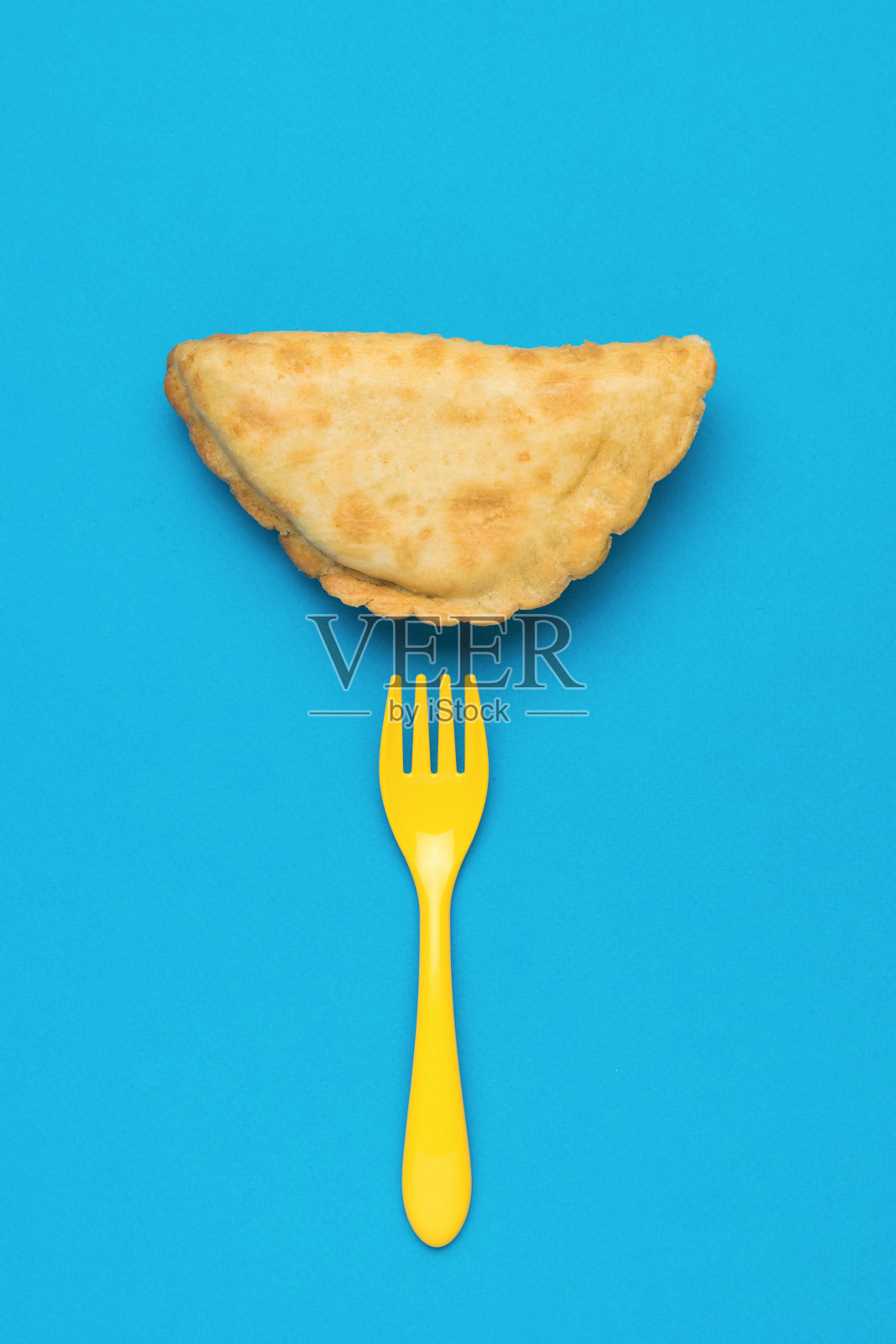 蓝色背景下的黄色叉子和新鲜的切布里克。照片摄影图片