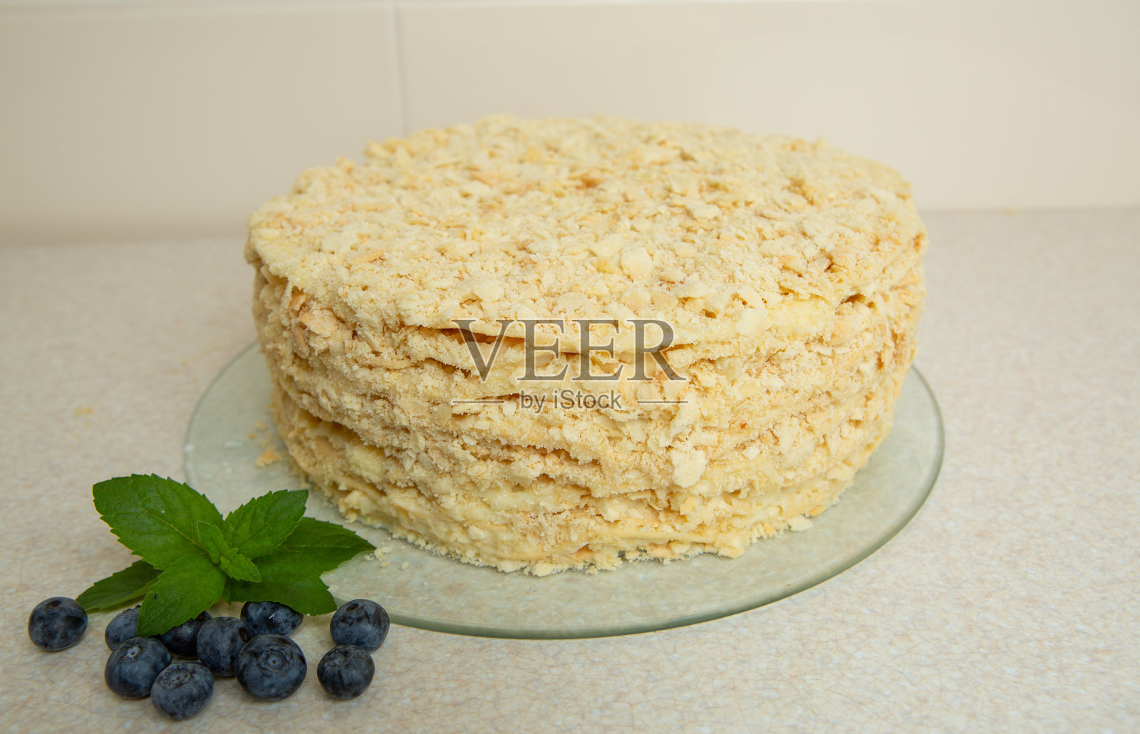 自制的拿破仑蛋糕在桌子上。它用薄荷叶和蓝莓装饰照片摄影图片