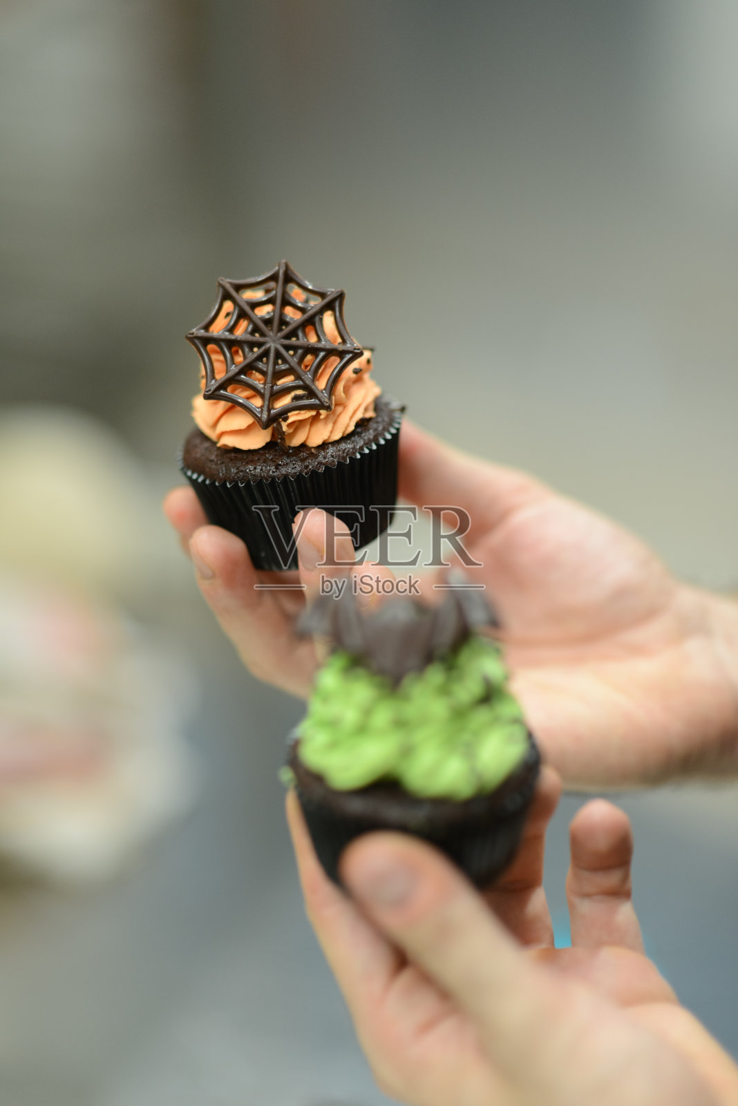 糕点师正在准备手工制作的万圣节绿橙怪兽纸杯蛋糕照片摄影图片