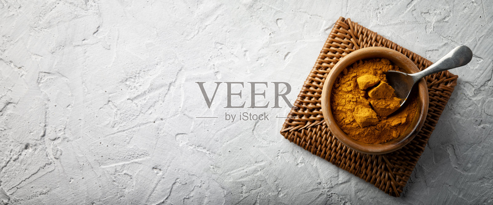 姜黄粉在木碗与勺子白色石膏背景,空间为文字,俯视图。照片摄影图片