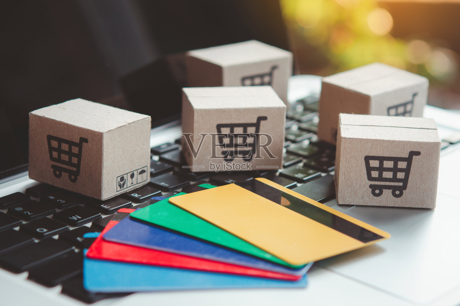 网上购物。信用卡和笔记本电脑键盘上有一个购物车标志的纸板箱。网上购物服务。提供送货上门照片摄影图片