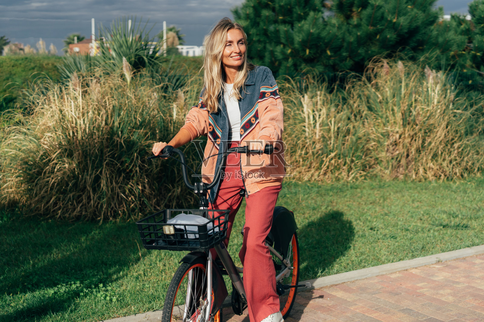 年轻快乐的女人骑着租来的电动自行车。照片摄影图片