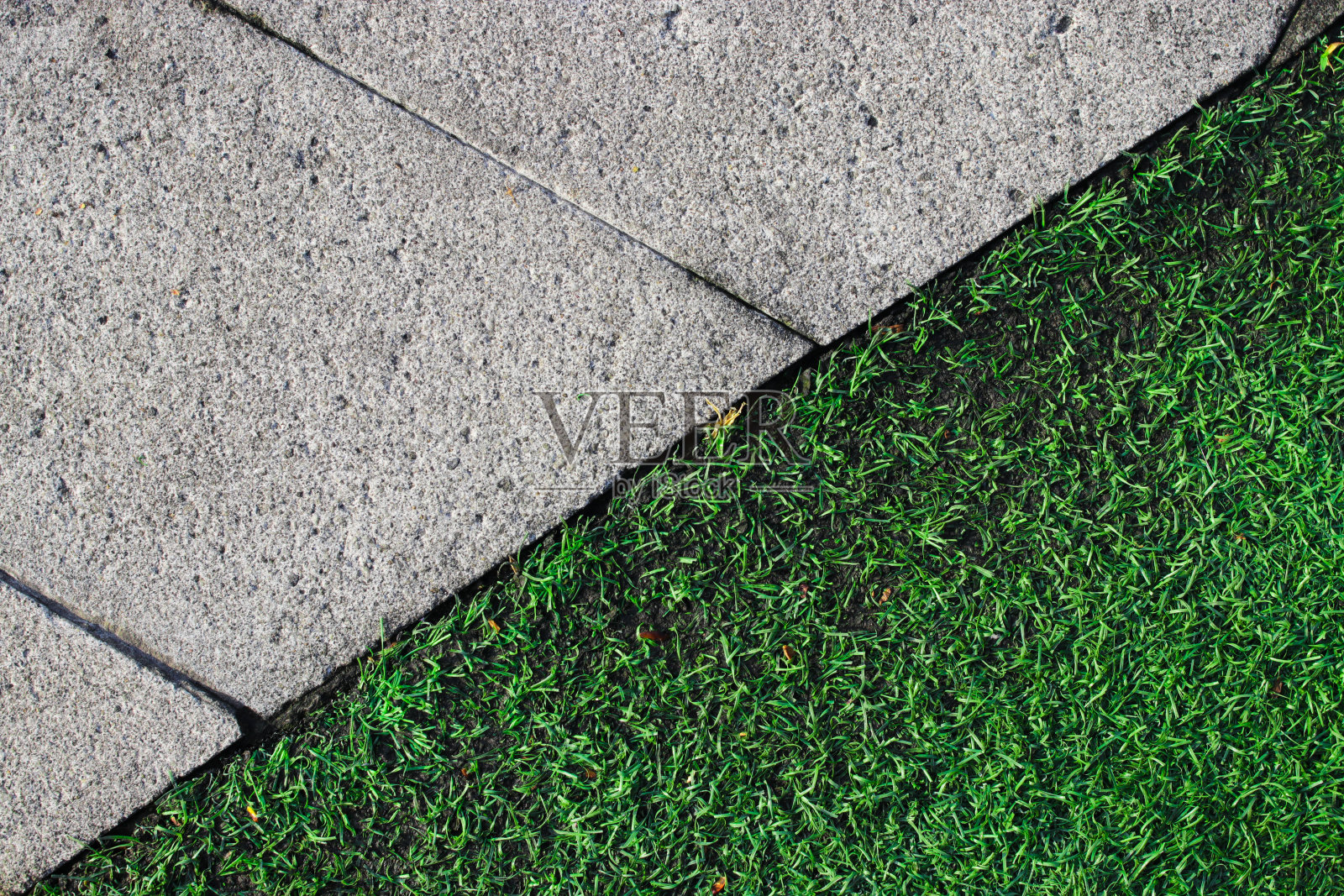 绿色草坪走道上的人造草皮和混凝土瓷砖。照片摄影图片