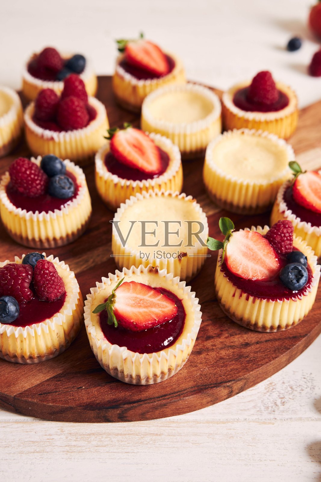 高角度拍摄的奶酪纸杯蛋糕,水果果冻和水果放在木盘子上照片摄影图片