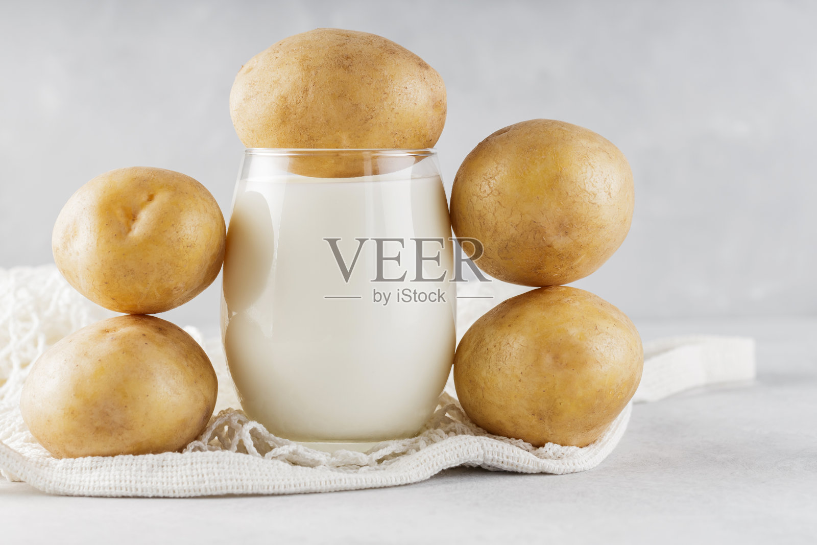 可选择玻璃土豆奶和土豆。可选择不含乳制品的饮料和绳袋。纯素土豆奶和可持续生活理念照片摄影图片
