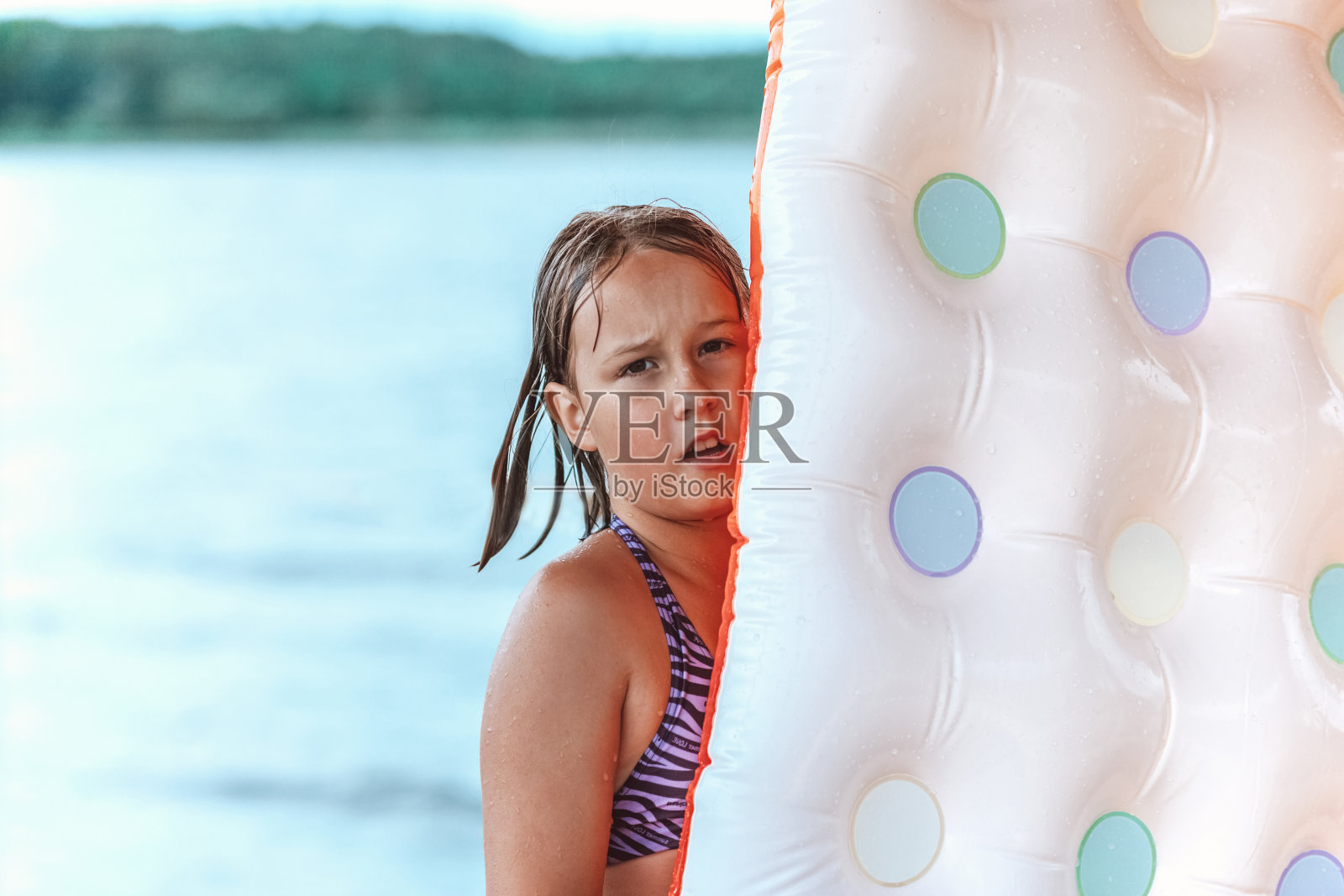 在湖边抱着充气床垫的可爱女孩照片摄影图片