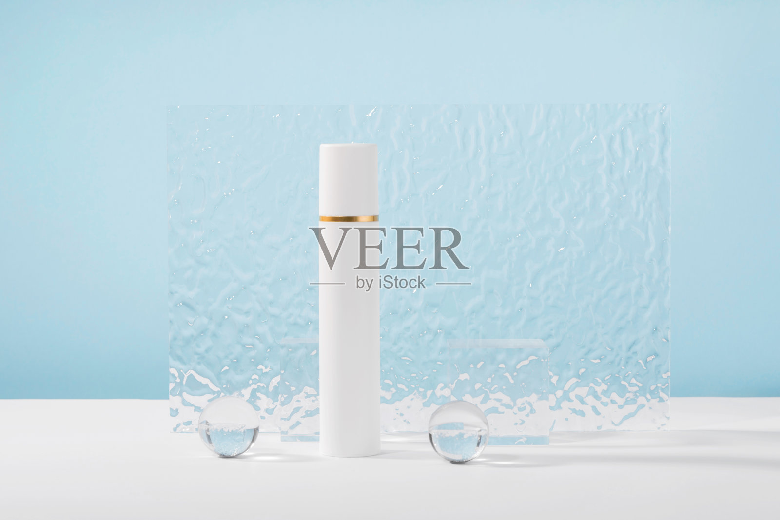 无品牌化妆品霜塑料管模型蓝色背景与时尚的道具,玻璃球和亚克力板。乳液,遮瑕膏或白色美容产品包装。产品演示模型照片摄影图片