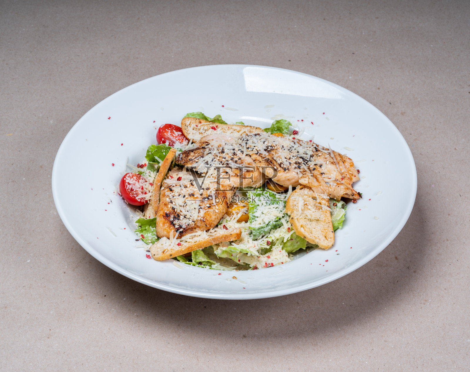 白色盘子上的凯撒沙拉特写。生菜,炸鸡,磨碎的奶酪,油炸面包丁。美味的餐厅食物。照片摄影图片