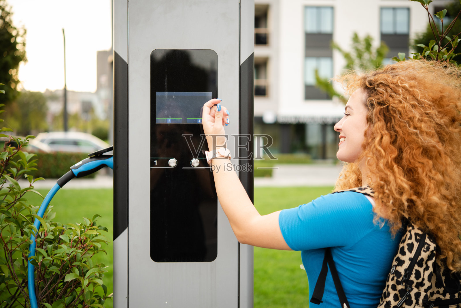 快乐的红发女人用她的智能手表在充电站付款照片摄影图片