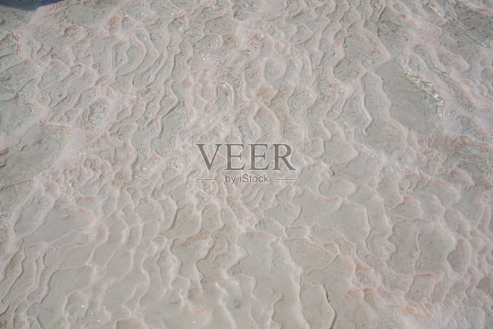 土耳其Pamukkale钙石灰华的石灰岩地板与水,不对称的图案特写。白色波浪质地。白色的钙石有质感。石灰岩。散焦图像。照片摄影图片