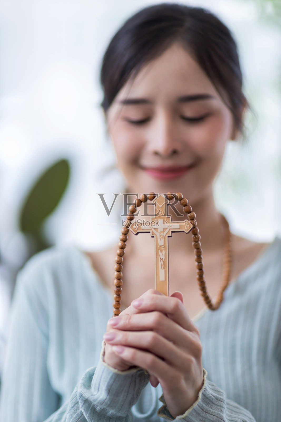 宗教中的女性观念。双手捧着十字架向上帝祈祷。修女手里拿着十字架。人类的双手握着一个神圣的十字架,祈求上帝的保佑。照片摄影图片