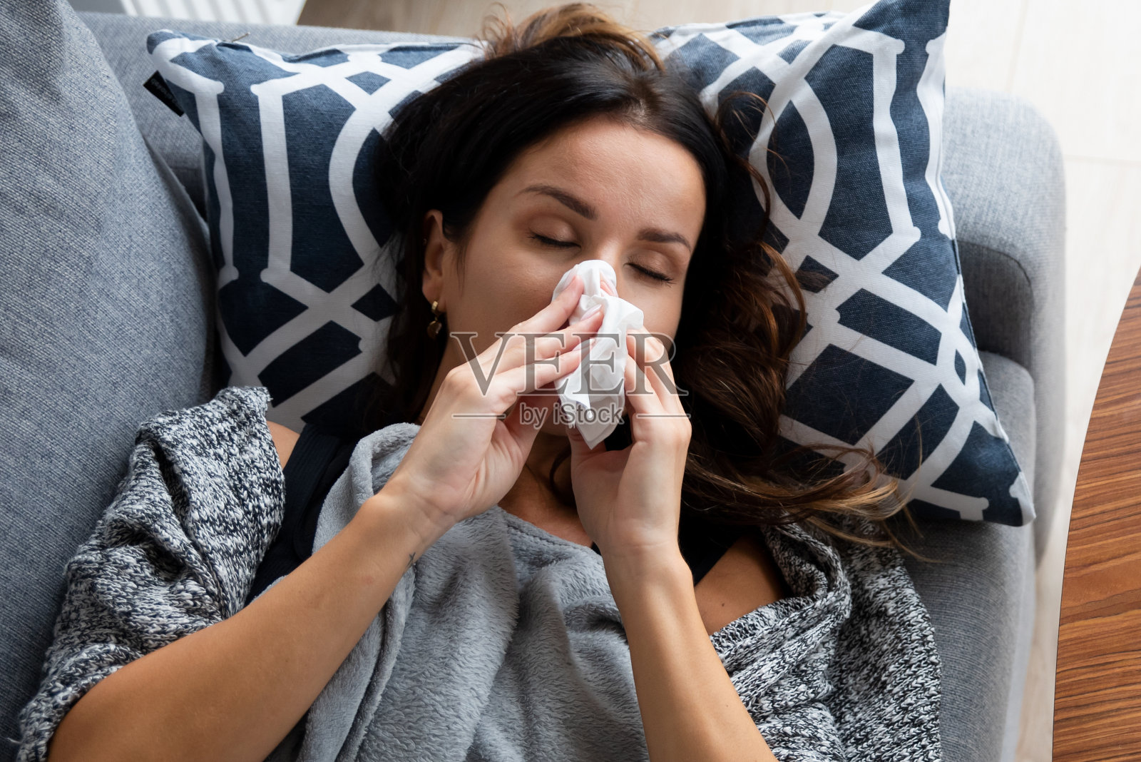 生病的女人躺在床上擤鼻子照片摄影图片