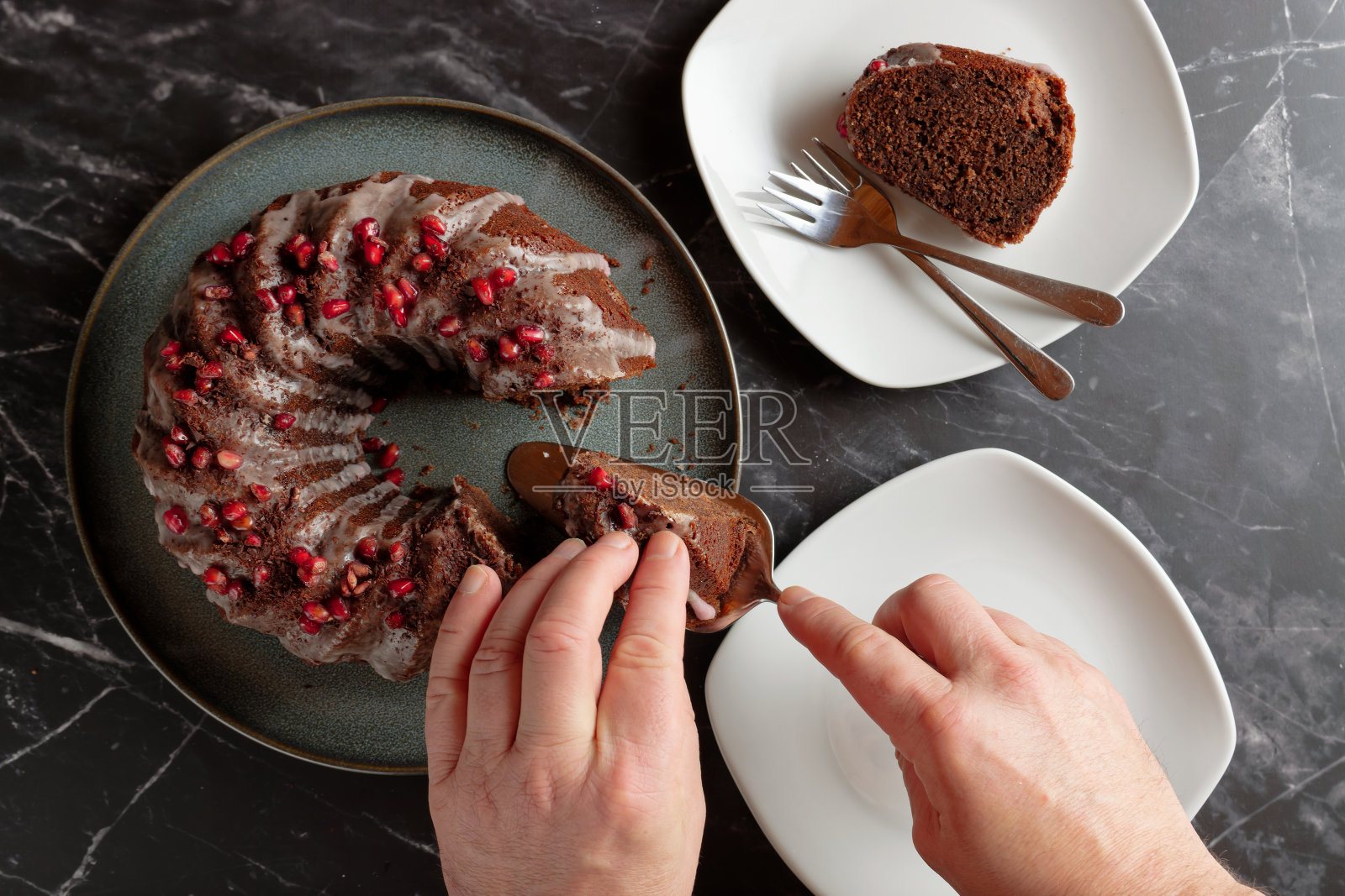 男士双手奉上热葡萄酒海绵蛋糕,配上糖衣和石榴籽。照片摄影图片
