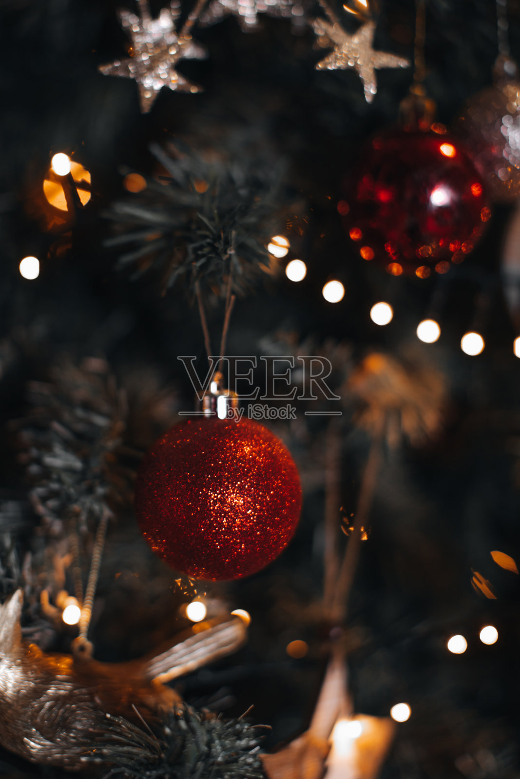 红色的圣诞球挂在圣诞树上。背景上有散景灯的神奇细节。照片摄影图片