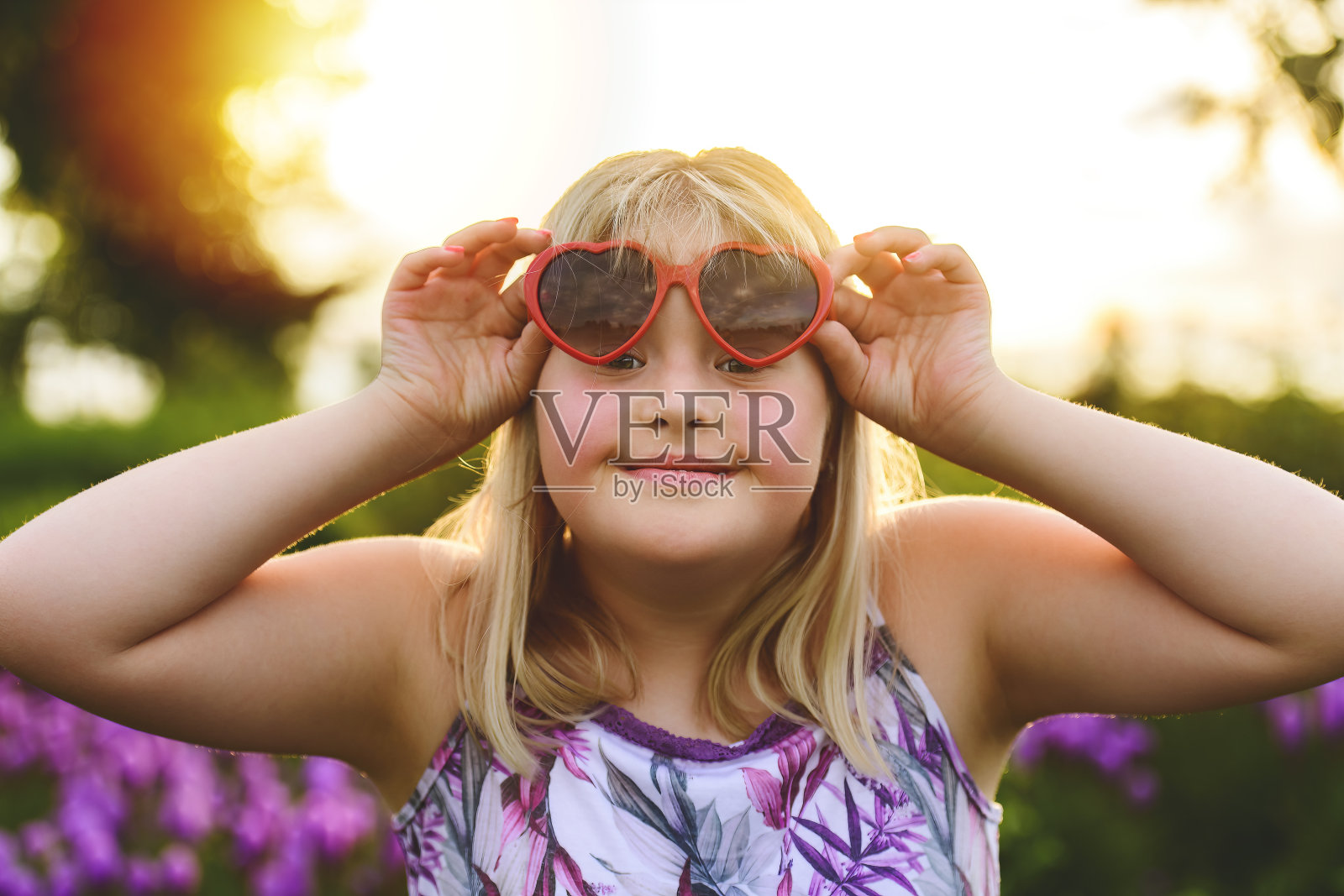 在夏日的夕阳下,带着爱的墨镜的小女孩的画像照片摄影图片