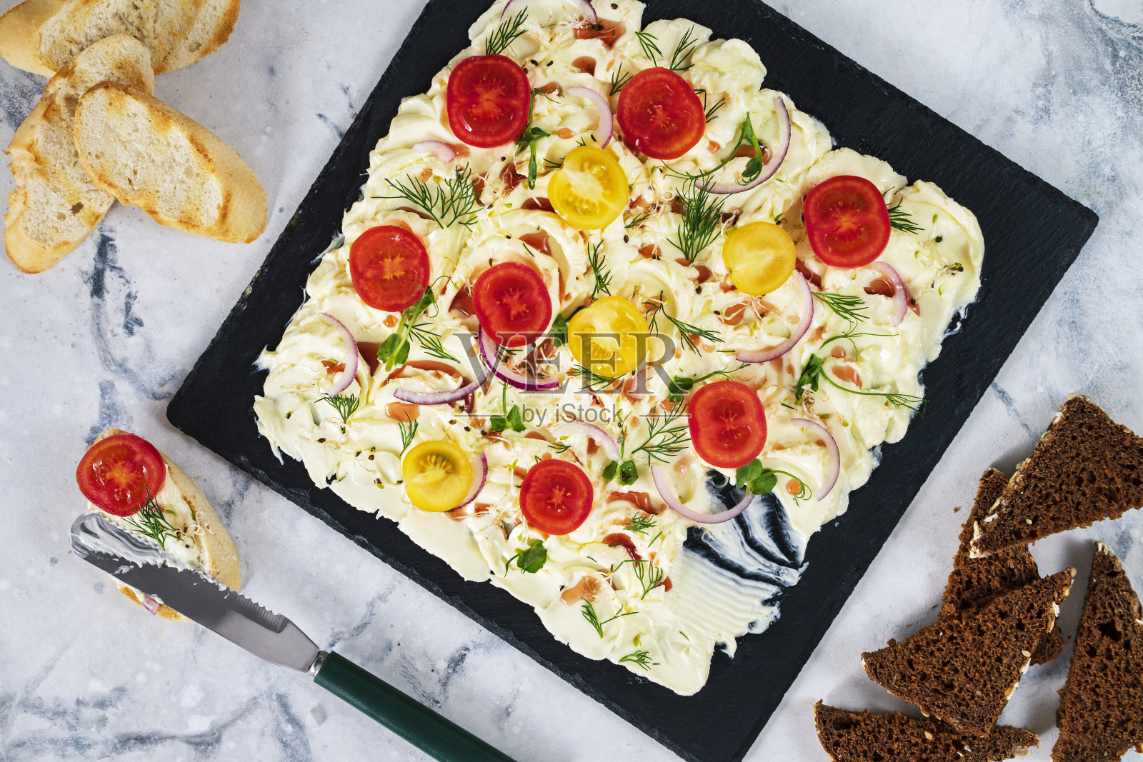 铺在一块黄油板上,上面放着红洋葱、圣女果,点缀着莳萝叶和微绿。桌面视图照片摄影图片