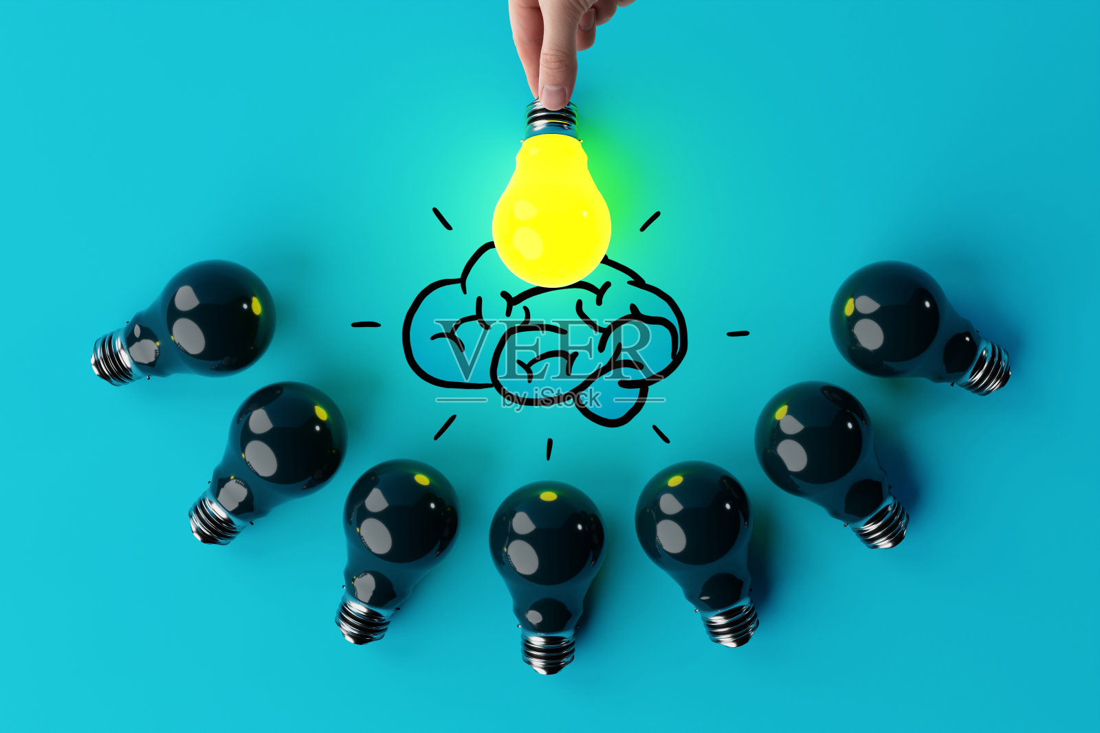 一只手拿着一个亮着的灯泡,背景是其他熄灭的灯泡和大脑的草图。照片摄影图片