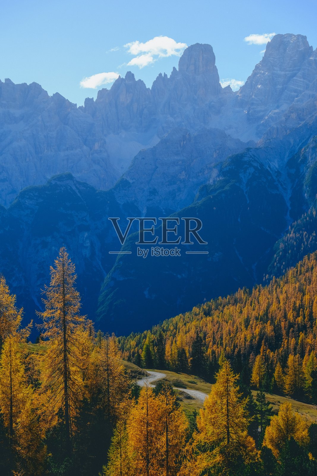 黄色的树和山的垂直镜头,蓝色的天空为背景照片摄影图片