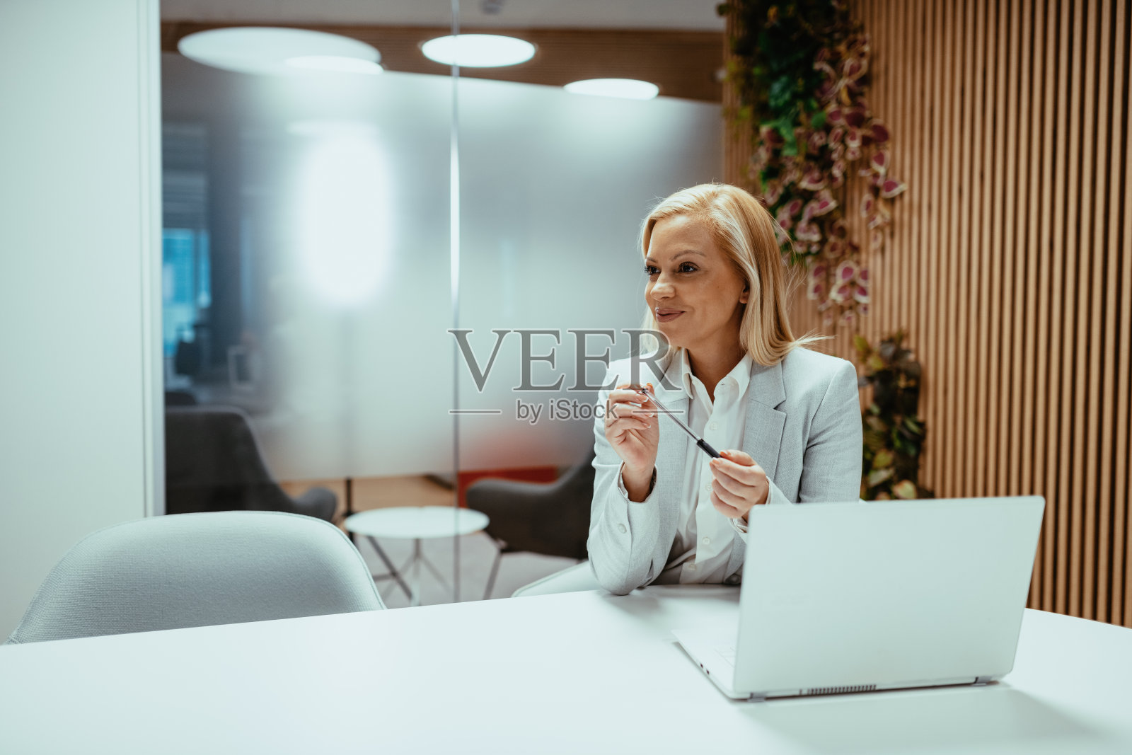 画像成熟的女商人穿着职业装,坐在现代办公室和使用笔记本电脑照片摄影图片