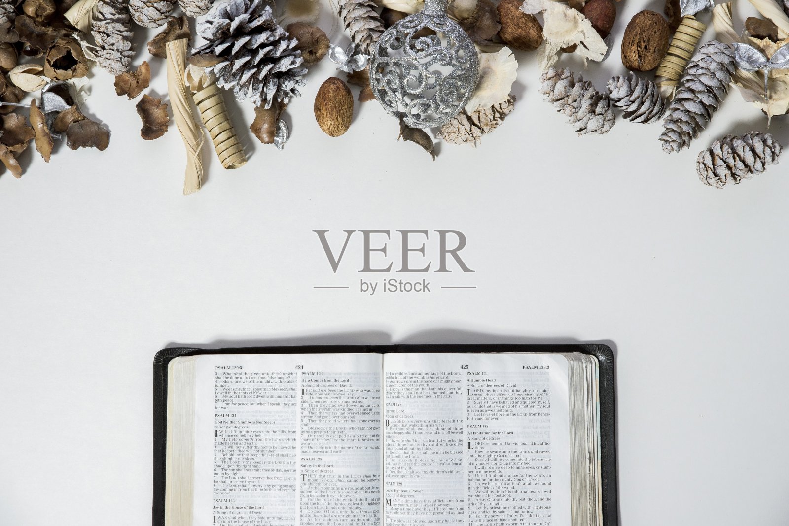头顶上一张打开的圣经靠近松果和白色表面上的装饰照片摄影图片