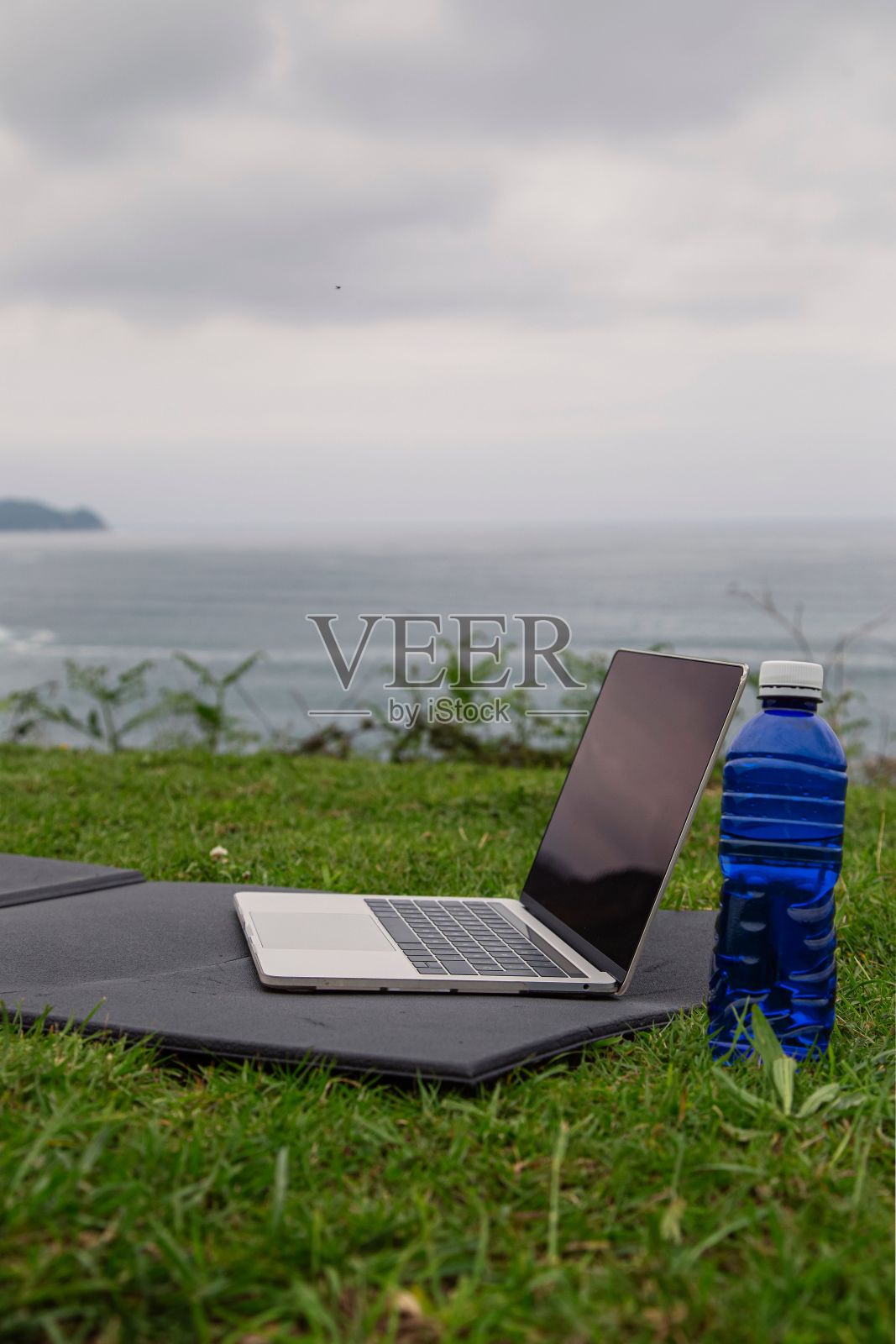 带瑜伽垫的笔记本电脑,户外的瓶装水。在线运动或瑜伽训练的概念。照片摄影图片