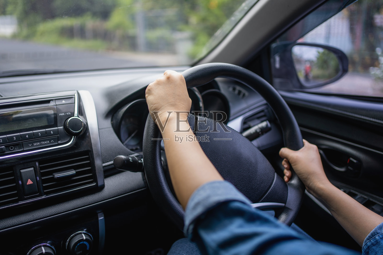 开车时,女性的手放在方向盘上。一个女人开车的手特写照片摄影图片