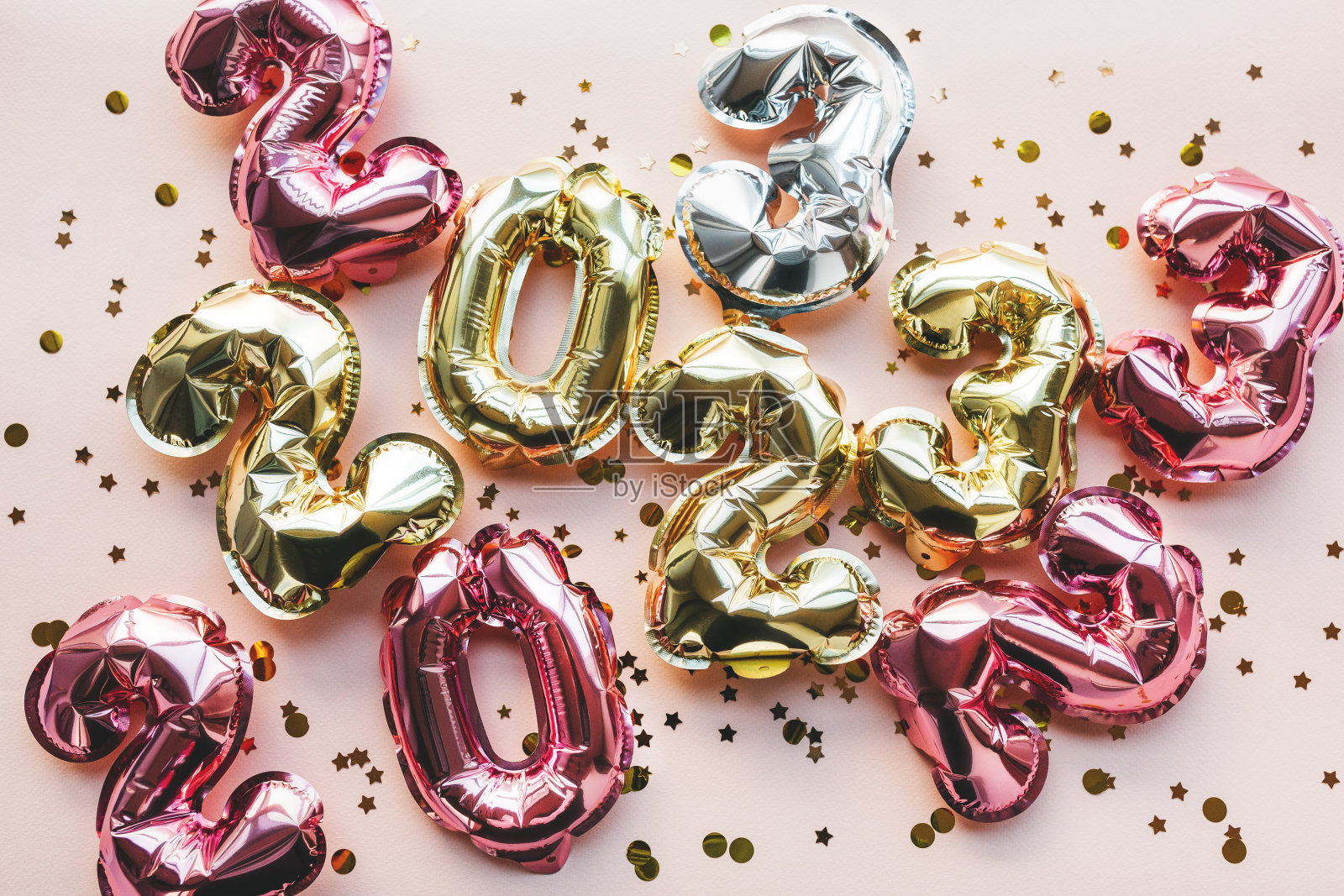 银色、金色、粉色的2023号彩色气球在粉红色的背景上用喜庆的彩纸杂乱地散落着。庆祝圣诞节,新年和节日的概念。平铺,俯视图。照片摄影图片