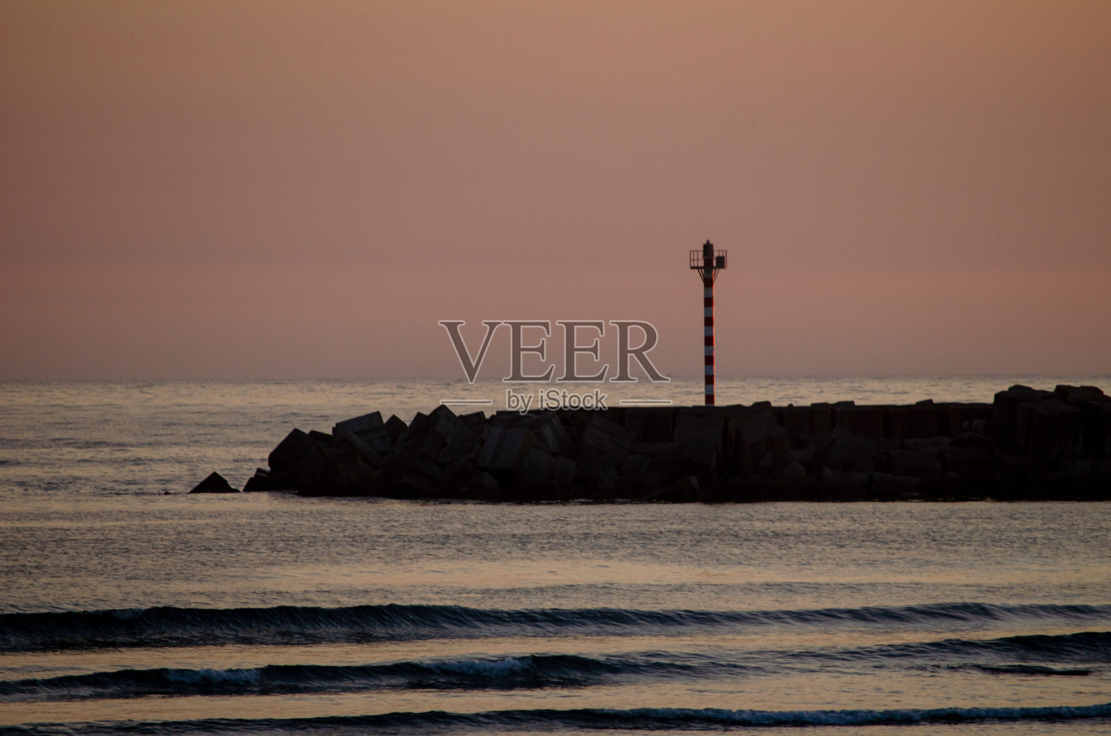 落日时分,岸边的红色金属灯塔照片摄影图片